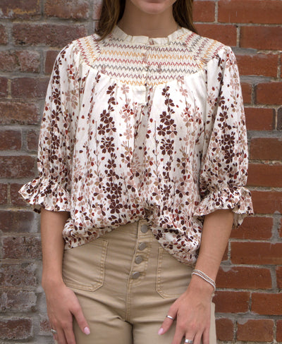Women’s vibrant floral top with smocked yoke, zig-zag stitching, puff sleeves, and button-front detail
