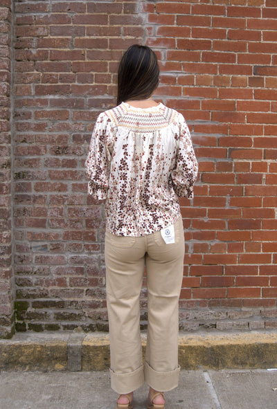 Women’s vibrant floral top with smocked yoke, zig-zag stitching, puff sleeves, and button-front detail