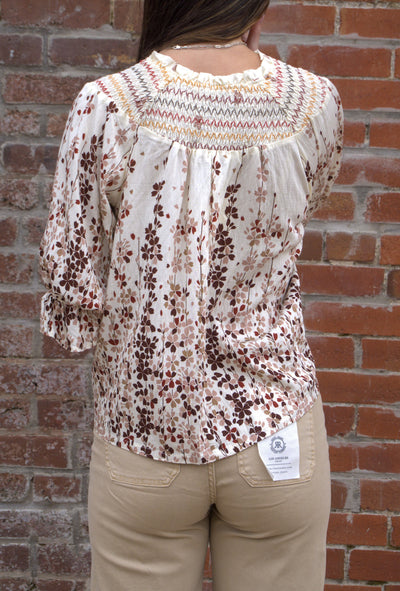 Women’s vibrant floral top with smocked yoke, zig-zag stitching, puff sleeves, and button-front detail