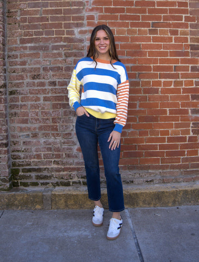Color block striped cotton sweater with ribbed round neckline in orange and blue, long sleeves, and soft knit texture.”